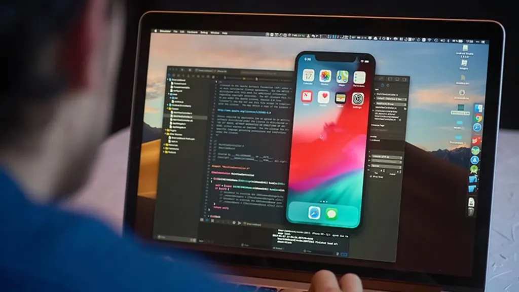 iOS app development process — MacBook with Xcode code editor and iPhone simulator during Swift App Development